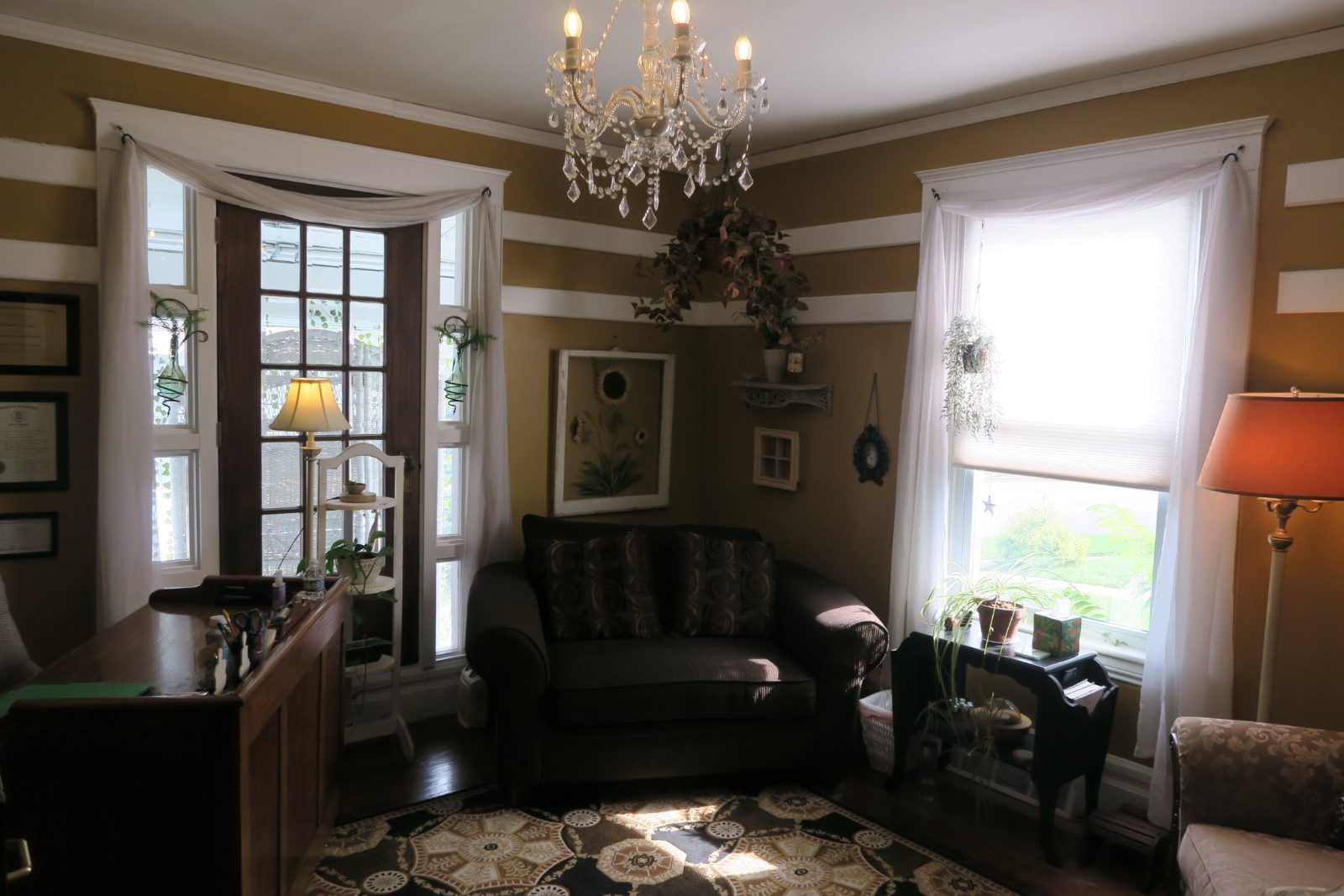 A gold-walled therapy office with a chandelier, leather sofa and patterned rug