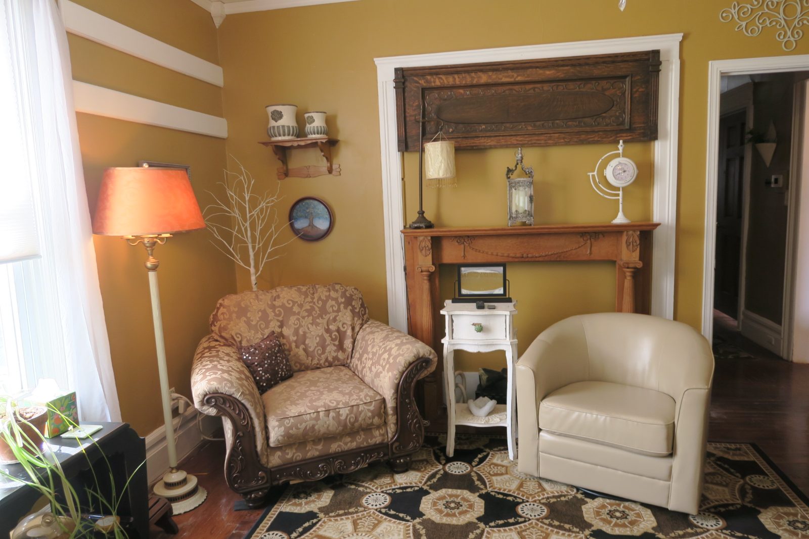 A cozy therapy office with two armchairs beside a wooden fireplace mantel