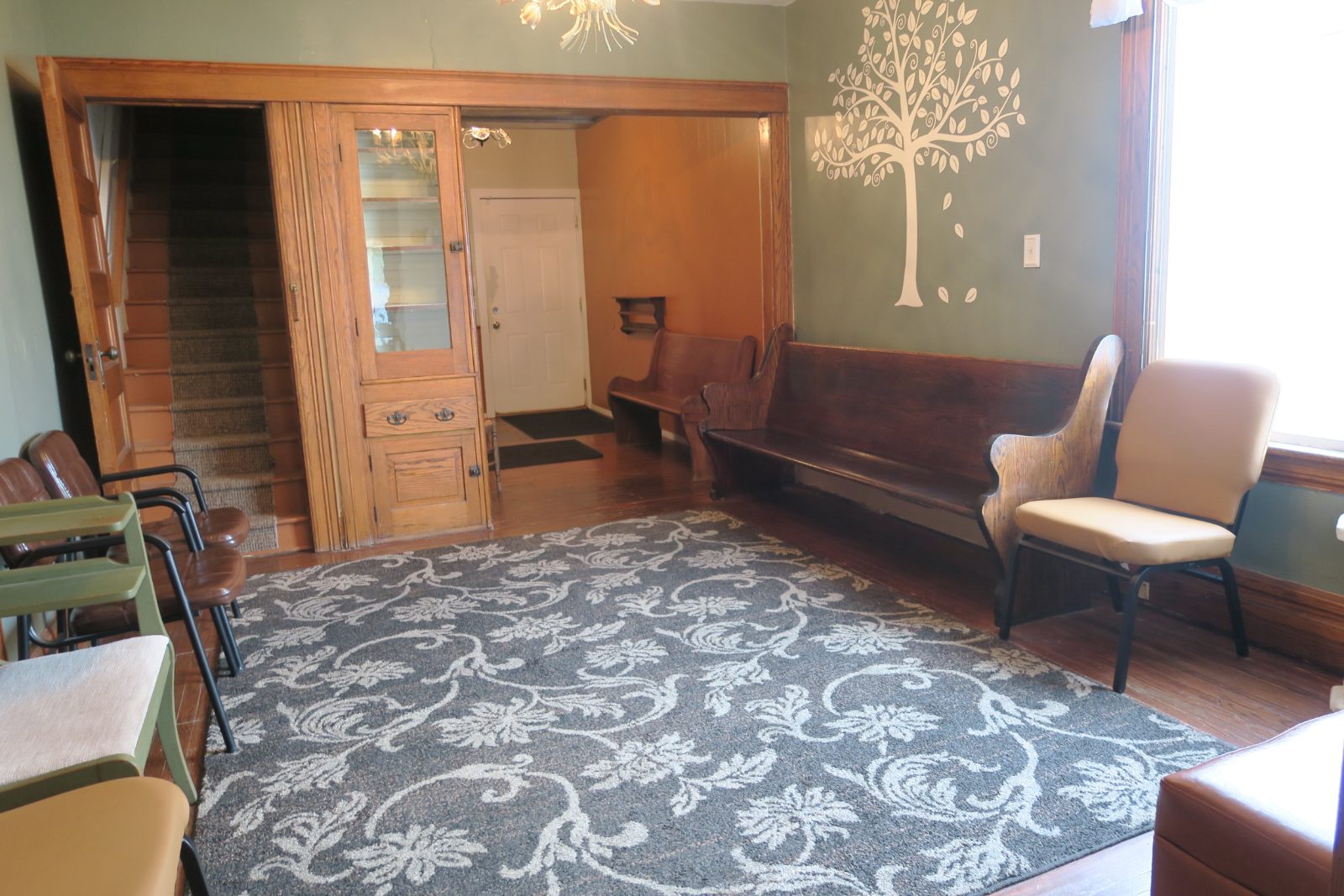 The waiting room at Lowder Psychology Group in Jackson, MI, with chairs, a staircase and a tree mural